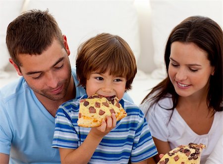 Happy boy eating pizza with ihs parents in living-room Stock Photo - Budget Royalty-Free & Subscription, Code: 400-04152231