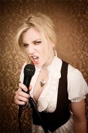 simsearch:400-04655366,k - Pretty young female blonde singer or comedian with microphone Stock Photo - Budget Royalty-Free & Subscription, Code: 400-04153033