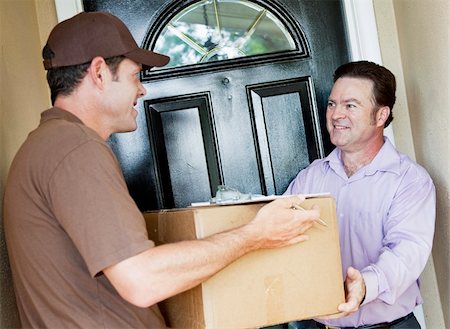 simsearch:400-04150533,k - Man receiving a package delivery from a courier at his home. Stockbilder - Microstock & Abonnement, Bildnummer: 400-04153096