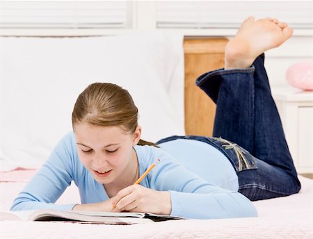 Young girl lying on bed doing homework.  Horizontally framed shot. Stock Photo - Budget Royalty-Free & Subscription, Code: 400-04164031