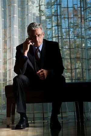 simsearch:400-04167566,k - Businessman in suit with serious expression sitting talking on a mobile phone. Vertical shot. Stockbilder - Microstock & Abonnement, Bildnummer: 400-04164290