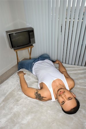 simsearch:400-04167868,k - High angle view of a young man lying on a bed and looking up at the camera with a bored expression. Vertical shot. Fotografie stock - Microstock e Abbonamento, Codice: 400-04167867