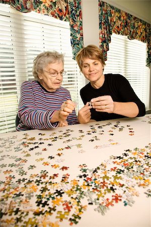 daughter helping elderly parent - Elderly woman and younger woman work on a jigsaw puzzle together.  Vertical shot. Stock Photo - Budget Royalty-Free & Subscription, Code: 400-04167935