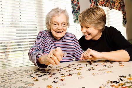 Elderly woman and a younger woman work on a jigsaw puzzle.  Horizontal shot. Foto de stock - Super Valor sin royalties y Suscripción, Código: 400-04167937