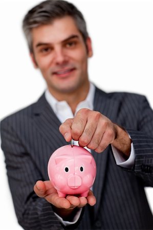 simsearch:400-05715051,k - Charismatic male executive saving money in a piggybank against a white background Fotografie stock - Microstock e Abbonamento, Codice: 400-04168035