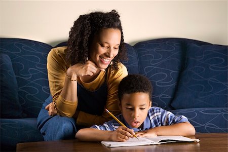 A mid adult African American woman sits on a couch and helps her young some with his homework. Horizontal shot. Stock Photo - Budget Royalty-Free & Subscription, Code: 400-04168197