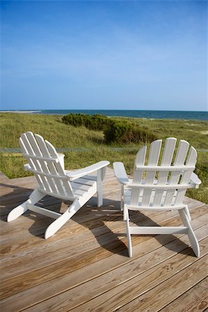 simsearch:400-03923118,k - Two Adirondack style chairs sitting on a wooden deck, facing the shore. The grassy beach is in view beyond the deck. Vertical shot. Fotografie stock - Microstock e Abbonamento, Codice: 400-04168274