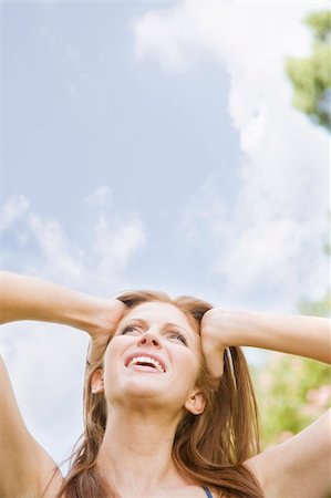 simsearch:6108-05867864,k - Image of a young woman outdoors with hands on her head, looking up and away from the camera. Head and shoulders viewable. Vertically framed shot. Stockbilder - Microstock & Abonnement, Bildnummer: 400-04168373