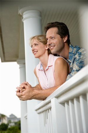 Smiling man and woman look out from a house porch leaning on the railing. Vertical shot. Stock Photo - Budget Royalty-Free & Subscription, Code: 400-04168795