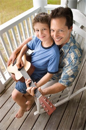 porch rocking chairs - Boy playing guitar while sitting on his father's lap. Vertical shot. Stock Photo - Budget Royalty-Free & Subscription, Code: 400-04168793