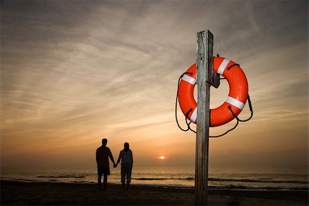 Silhouette of couple holding hands on beach watching the sunset with life preserver in foreground Stock Photo - Budget Royalty-Free & Subscription, Code: 400-04168813