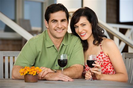 portrait photo of people socialising in a cafe - Man and woman smile towards the camera at an outdoor cafe holding glasses of wine. Horizontal shot. Stock Photo - Budget Royalty-Free & Subscription, Code: 400-04168866