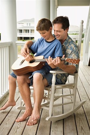 father playing guitar - Son sits on his father's lap while playing guitar. Vertical shot. Stock Photo - Budget Royalty-Free & Subscription, Code: 400-04168956