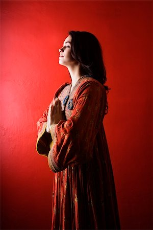 simsearch:6108-06905650,k - Attractive young woman standing against a red wall with hands held in prayer and eyes closed. Vertical shot. Isolated on red. Stock Photo - Budget Royalty-Free & Subscription, Code: 400-04169071