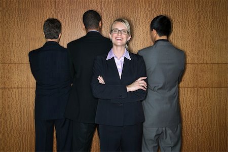 Caucasian businesswoman stands smiling as businessmen stand with their backs turned. Horizontal shot. Stock Photo - Budget Royalty-Free & Subscription, Code: 400-04169106