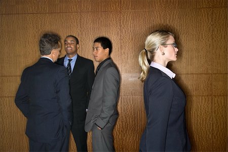 segregación - Businessmen of ethnic diversity talk in a group as a Caucasian businesswoman walks by. Horizontal shot. Foto de stock - Super Valor sin royalties y Suscripción, Código: 400-04169107