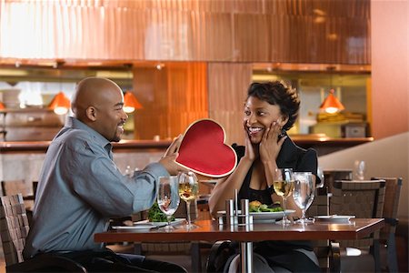 simsearch:400-04655735,k - African-American gives a Valentine Day heart box to a surprised woman at a restaurant. Horizontal shot. Stockbilder - Microstock & Abonnement, Bildnummer: 400-04169140