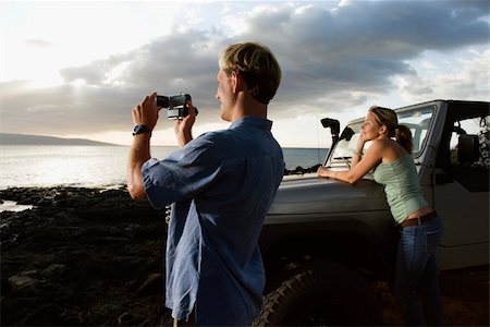 Woman leaning on an SUV while man video records scenery on a beach. Horizontal format. Stock Photo - Budget Royalty-Free & Subscription, Code: 400-04169285