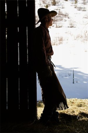 Silhouette of a cowboy leaning in a barn doorway, looking outside. Vertical shot. Stock Photo - Budget Royalty-Free & Subscription, Code: 400-04169398
