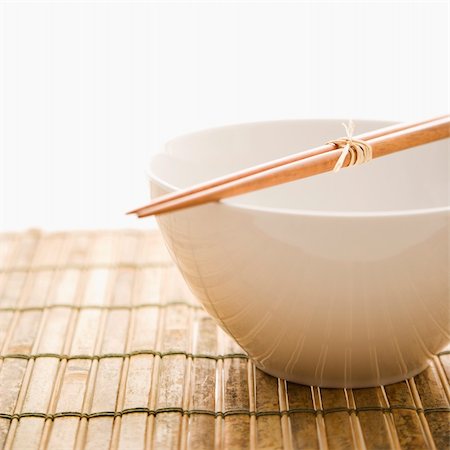 Chopsticks lying across an empty bowl on a bamboo mat. Square format. Isolated on white. Stock Photo - Budget Royalty-Free & Subscription, Code: 400-04169594