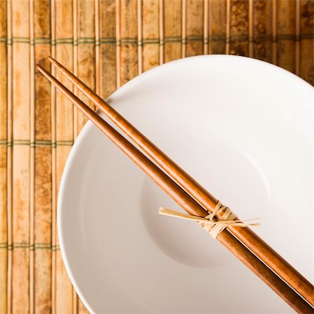 Overhead view of chopsticks lying across an empty bowl on a bamboo mat. Square format. Stock Photo - Budget Royalty-Free & Subscription, Code: 400-04169592