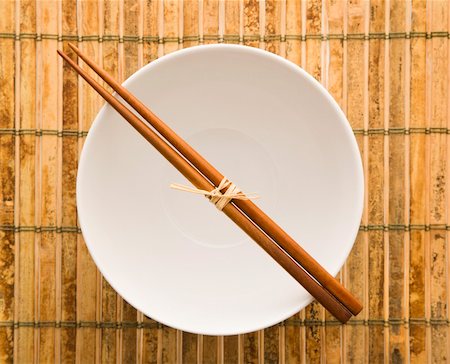 Overhead view of chopsticks lying across an empty bowl on a bamboo mat. Horizontal format. Stock Photo - Budget Royalty-Free & Subscription, Code: 400-04169593