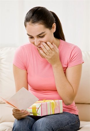 Young woman reading card and holding gift-wrapped present. Vertically framed shot. Stock Photo - Budget Royalty-Free & Subscription, Code: 400-04161346
