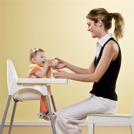 photo of mother feeding baby high chair - Young woman feeding bottle to baby girl in high chair.  Square framed shot. Stock Photo - Budget Royalty-Free & Subscription, Code: 400-04161962