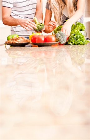 simsearch:400-04162443,k - Young couple picks through fresh vegetables at the far end of a kitchen counter. Vertical shot. Fotografie stock - Microstock e Abbonamento, Codice: 400-04162439