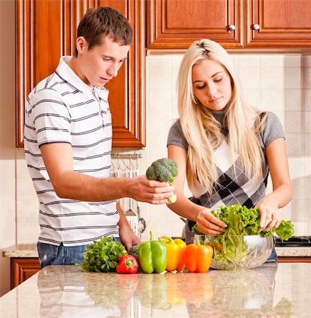 simsearch:400-04162443,k - Young couple in kitchen make salad with fresh vegetables. Square shot. Fotografie stock - Microstock e Abbonamento, Codice: 400-04162431