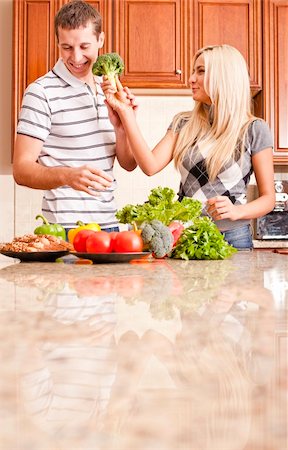 Young couple in a kitchen joke around with fresh vegetables. Vertical shot Stock Photo - Budget Royalty-Free & Subscription, Code: 400-04162440