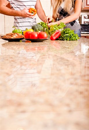 simsearch:400-04162443,k - Young couple picks through fresh vegetables at the far end of a kitchen counter. Vertical shot. Fotografie stock - Microstock e Abbonamento, Codice: 400-04162442