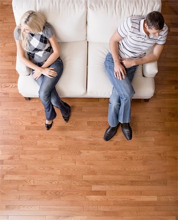 Man and a woman sit distantly on the ends of a cream colored love seat. Their heads are turned away from each other. Vertical shot. Stock Photo - Budget Royalty-Free & Subscription, Code: 400-04162574