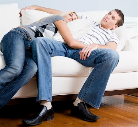 Woman snuggles up to man as they both relax quietly on a white couch. Horizontal format. Fotografie stock - Microstock e Abbonamento, Codice: 400-04162690