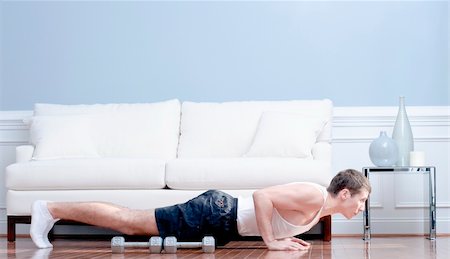 Full length view of man doing push-ups next to couch, with arm weights lying next to him. Horizontal format. Stock Photo - Budget Royalty-Free & Subscription, Code: 400-04162692