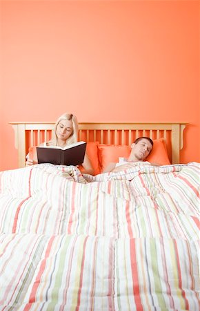 simsearch:640-01355958,k - View of couple in bed, with woman reading book and man sleeping. Vertical format. Stock Photo - Budget Royalty-Free & Subscription, Code: 400-04162792