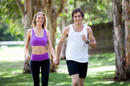 Portrait of a smiling young couple exercising in an outdoor setting while holding hands. The man is jogging, and the woman is walking. Horizontal shot. Stock Photo - Budget Royalty-Free & Subscription, Code: 400-04175821