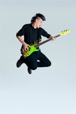 simsearch:400-04165960,k - Awesome mohawk man jumps with his guitar in studio Stock Photo - Budget Royalty-Free & Subscription, Code: 400-04175904