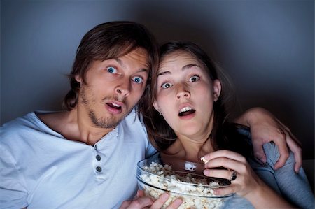 suspense - Young couple at home watching a movie with popcorn Fotografie stock - Microstock e Abbonamento, Codice: 400-04175950