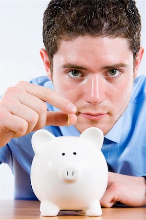 Stock image of man depositing coin into piggy bank Stock Photo - Budget Royalty-Free & Subscription, Code: 400-04179373