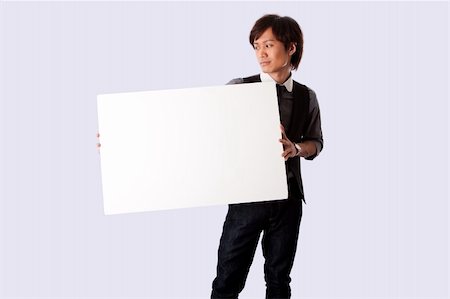 employee hold a sign - Young Asian business student man standing holding a white blank board and looking at it, isolated. Stock Photo - Budget Royalty-Free & Subscription, Code: 400-04172187