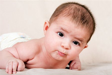 Cute Caucasian Hispanic baby infant laying on belly lifting head making funny expression. Stock Photo - Budget Royalty-Free & Subscription, Code: 400-04172207