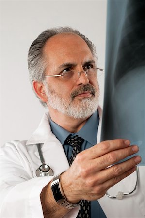 edbockstock (artist) - Portrait of a doctor wearing eyeglasses and a white lab coat and looking intently at an x-ray. Vertical shot. Isolated on white. Photographie de stock - Aubaine LD & Abonnement, Code: 400-04172665