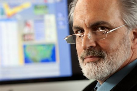 edbockstock (artist) - Close-up portrait of a businessman wearing eyeglasses and looking at the camera with a computer monitor in the background. Horizontal shot. Photographie de stock - Aubaine LD & Abonnement, Code: 400-04172663