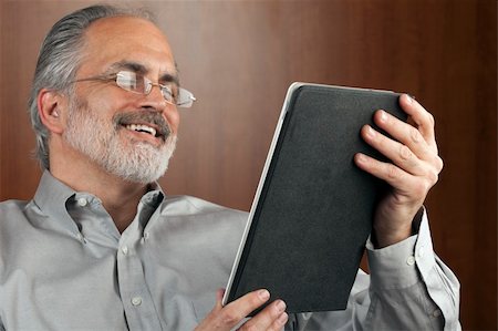 edbockstock (artist) - Portrait of a smiling businessman reading information from an electronic tablet. Horizontal shot. Photographie de stock - Aubaine LD & Abonnement, Code: 400-04172674