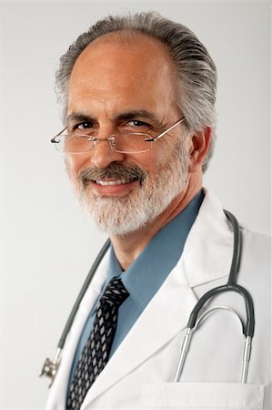 edbockstock (artist) - Portrait of a doctor wearing glasses and a white lab coat, with a stethoscope draped around his neck.  He is looking at the camera and smiling. Vertical format. Photographie de stock - Aubaine LD & Abonnement, Code: 400-04172671