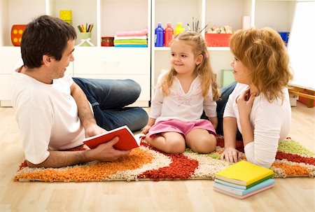 simsearch:400-04131892,k - Story time - happy family with a child reading a book laying on the floor Stockbilder - Microstock & Abonnement, Bildnummer: 400-04173034