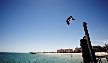 Boy doing a back flip off a pole into the sea in Australia Fotografie stock - Microstock e Abbonamento, Codice: 400-04173243