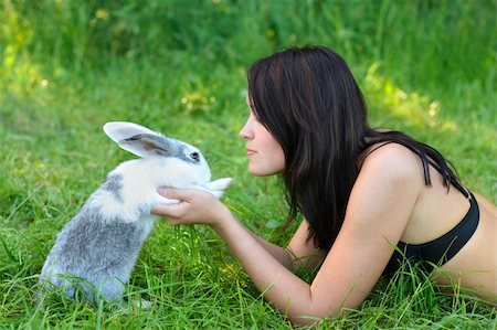 A young woman laying on the grass holds a rabbit Stockbilder - Microstock & Abonnement, Bildnummer: 400-04184615