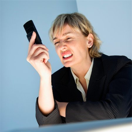 simsearch:400-04186486,k - Caucasian businesswoman looking at cellphone and sneering in frustration. Stock Photo - Budget Royalty-Free & Subscription, Code: 400-04186187